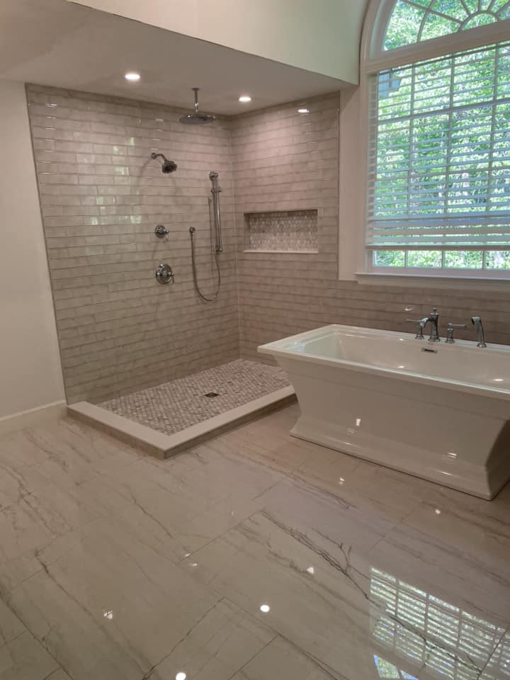 Subway tile shower with freestanding tub on marble floor by Peter's Tile