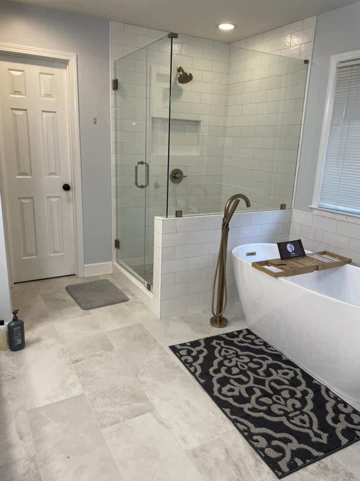 Glass-enclosed shower with freestanding tub by Peter's Tile