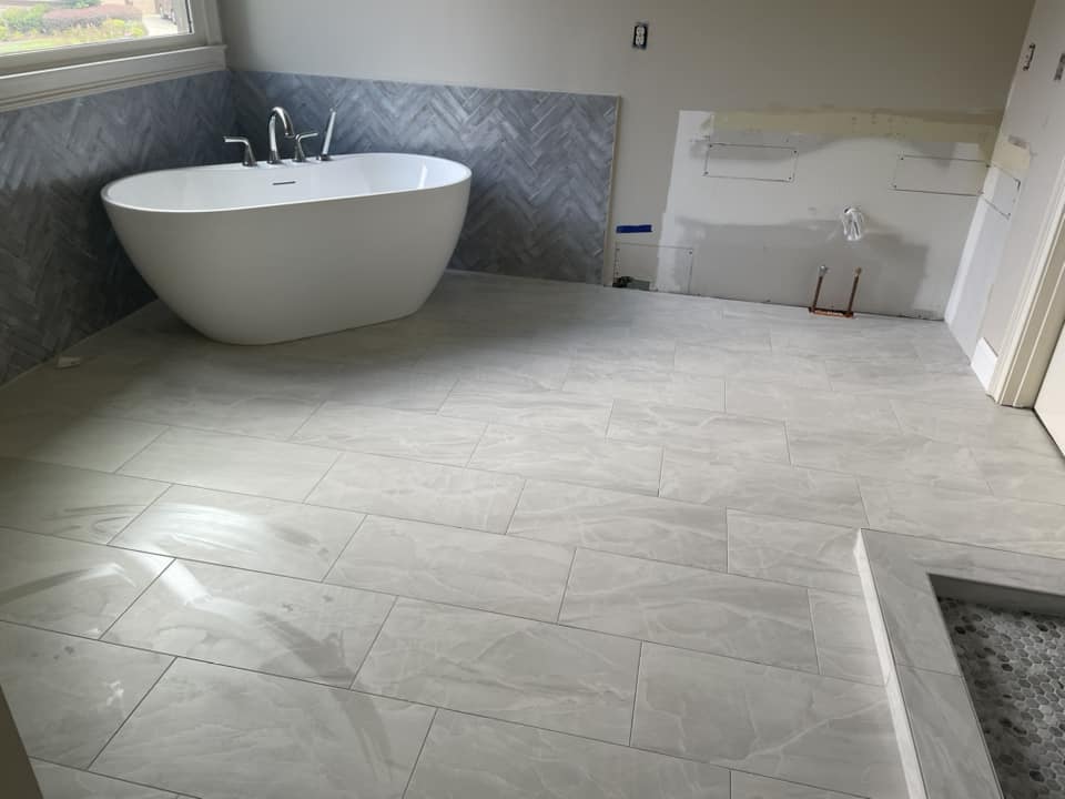 Freestanding tub on a large-format tile floor by Peter's Tile